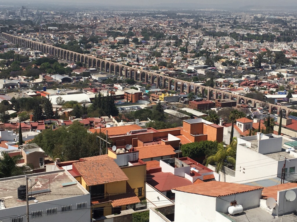 A view of Queretaro, Mexico, from high up on a mountain. Featured is the famous aqueduct, cutting across the photo from left to right. Cost of living Queretaro Mexico