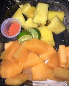 A gluten free or sin gluten meal I grabbed in the airport. I ate well in Mexico with celiac. Pictured: limes, cantaloupe, pineapple, and a container of a red spice. 