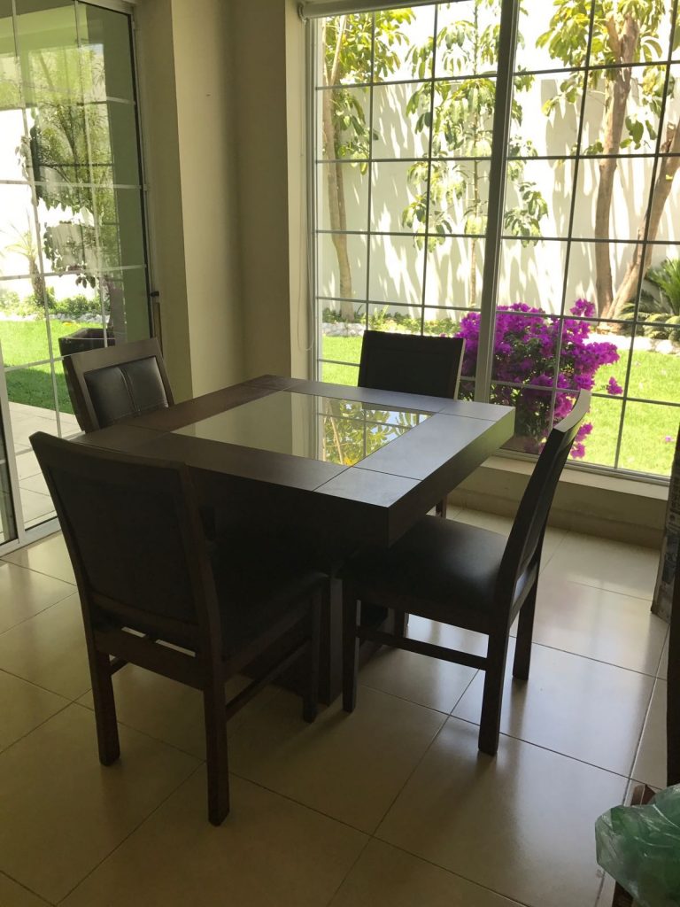 A kitchen table and chairs. Outside, a plant with pink flowers makes it look like heaven. 