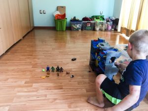 A young boy plays with batman toys.