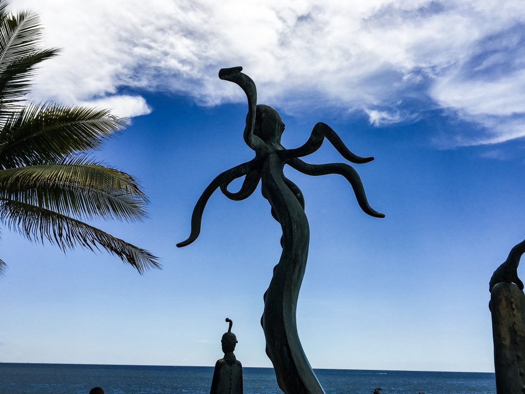 A statue of an octopus raised up on an artistic pole of sorts