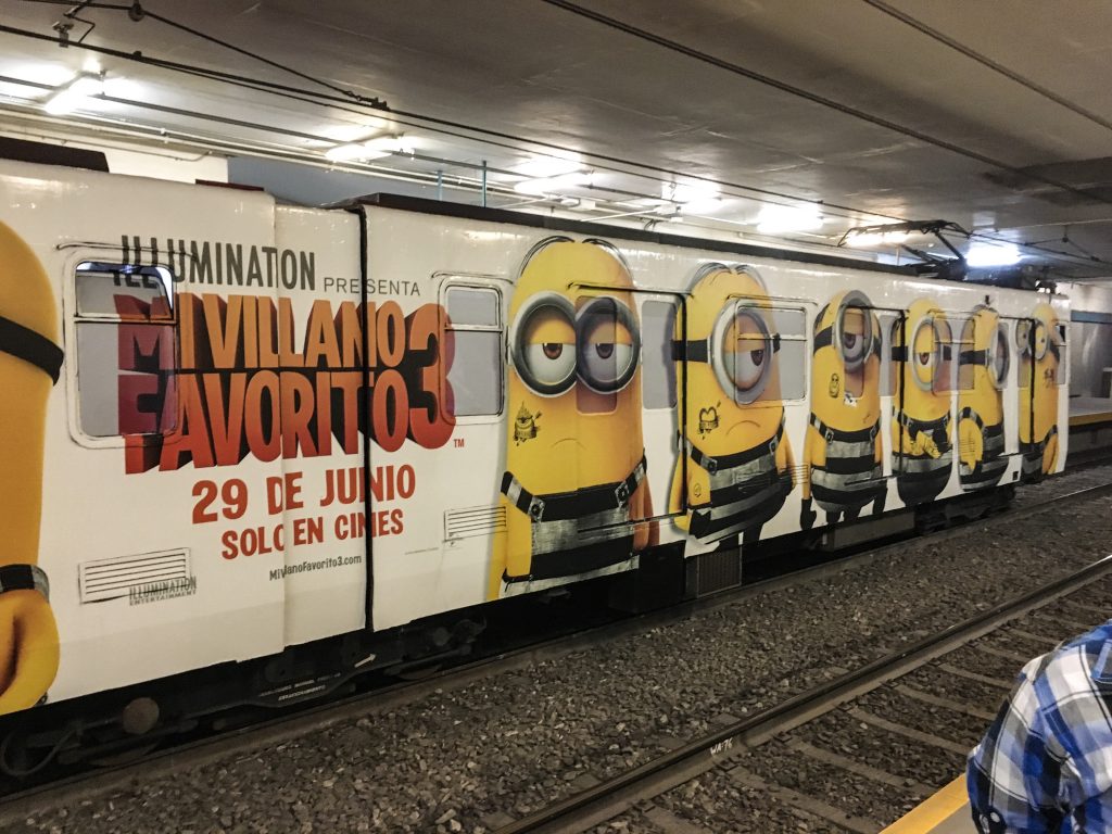 a subway train car is decked out with an advertisement for Despicable Me 3 in Spanish, with giant minions painted on.