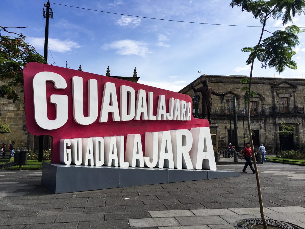 The Guadalajara city sign. White letters on a red background.