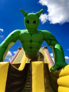 A giant inflatable slide with a green genie on top who resembles Shrek.