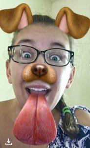 Using a snapchat filter, a woman (me) looks like she's part dog, including a large pink tongue that is sticking out of her mouth. Technology!.