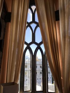 The gothic style windows with peach colored curtains.