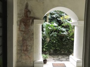 a mural on a wall, next to an open arch to the garden of the hotel.