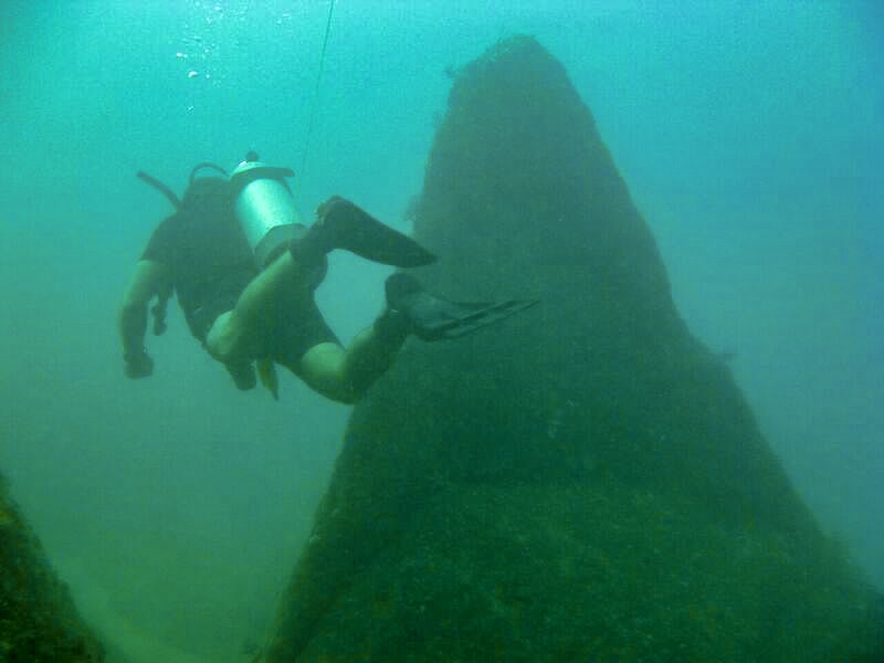 a diver, swimming away from us, with a natural rock formation to his (and our) right. I blieve diving in one way to have ethical animal encounters in the Caribbean.