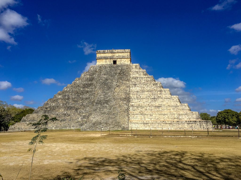 The famous pyramid of Chichen Itza. Three quarters of the pyramid is not restored and the remaining third is restored, showing up as a brighter, off white stone color.