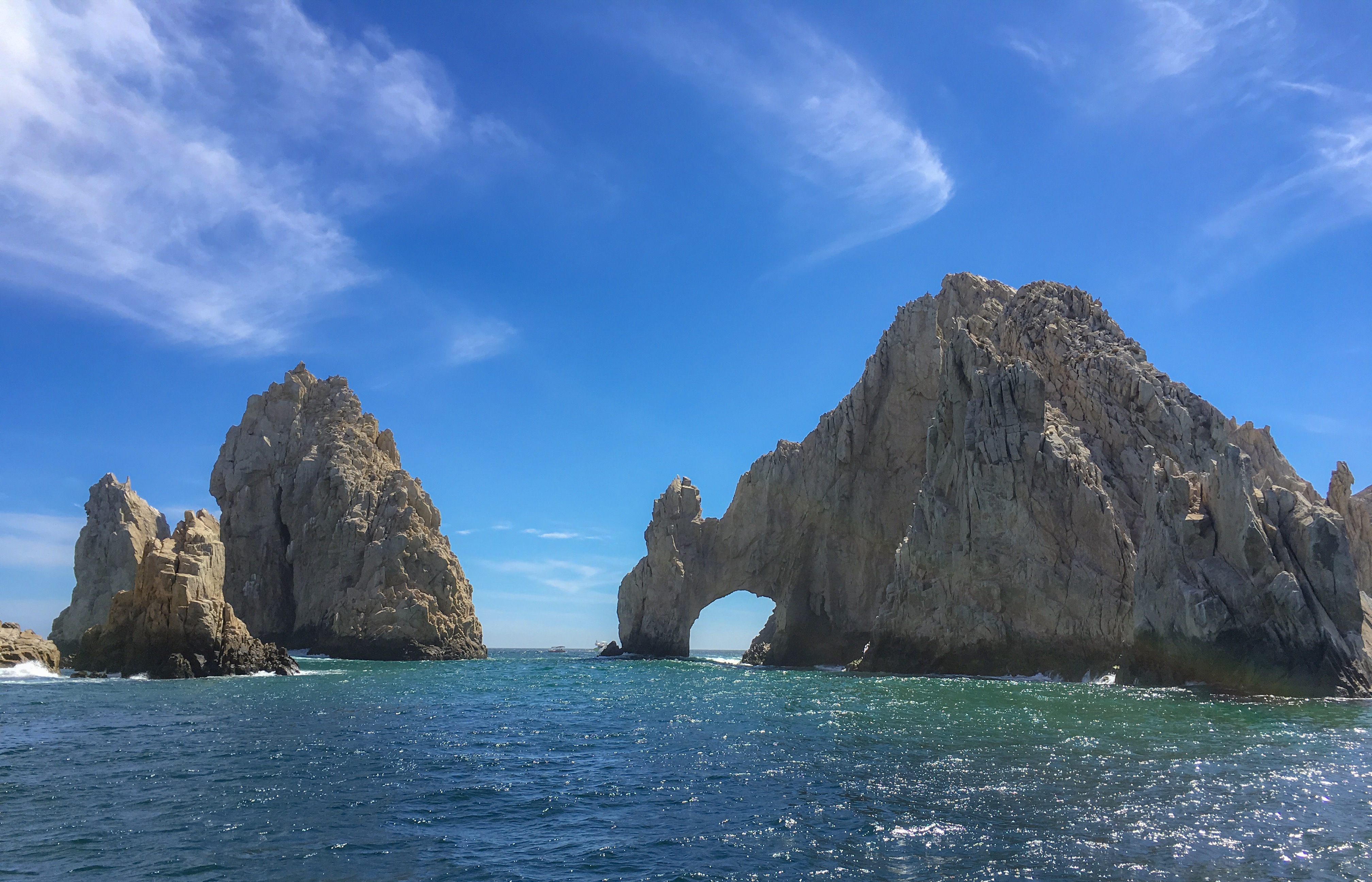 ocean in the foreground, in the background is the rock formation called Los Arcos because it's shaped like an arch.