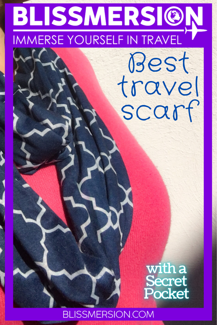 a blue and white infinity scard is featured on a model, wearing a pink sweater. The words best travel scarf wiht a secret pocket are on this pinterest image, from Guide to the Best Travel Scarf with Hidden Zipper Pocket 