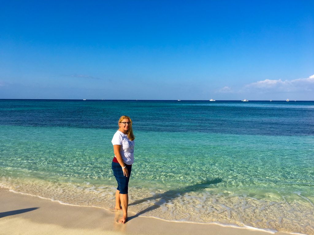 a woman poses in front of the impossible turquoise and deep blue of the ocean.