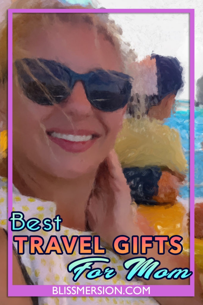 A blonde, smiling woman wearing sunglasses sits facing the camera, with a small amount of blue ocean behind her, with an artistic filter and the text says: Best travel gifts for mom.