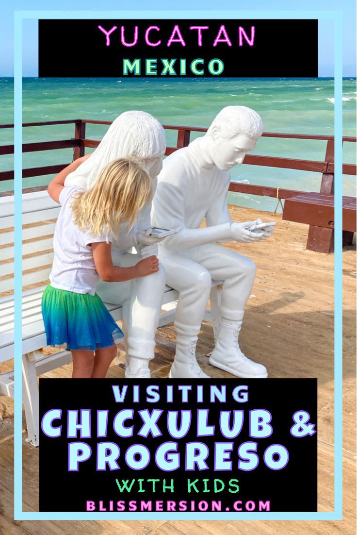 Pinterest image: Yucatan Mexico. Visiting Chicxulub and Progreso with kids. the background is a green and blue ocean, bright blue sky. A young blonde girl pretends to look at the phone of one of two white statues, both of whom are staring at phones in their hands. The girl faces away from the camera. The statues face away from the beautiful view.